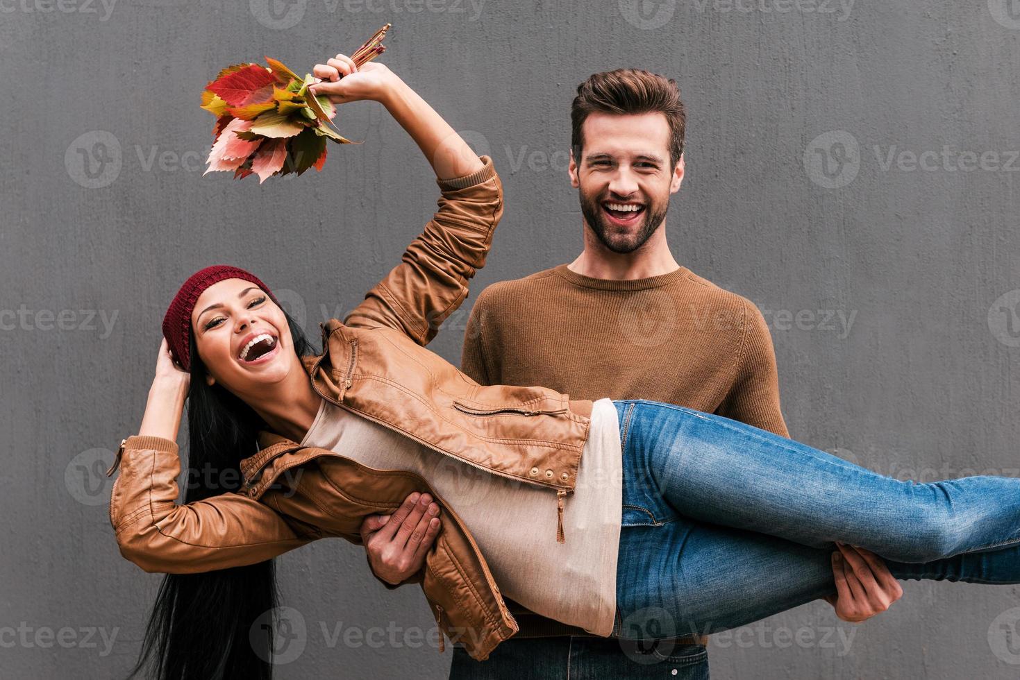 amor e diversão. lindo casal jovem se divertindo juntos em pé contra a parede cinza foto