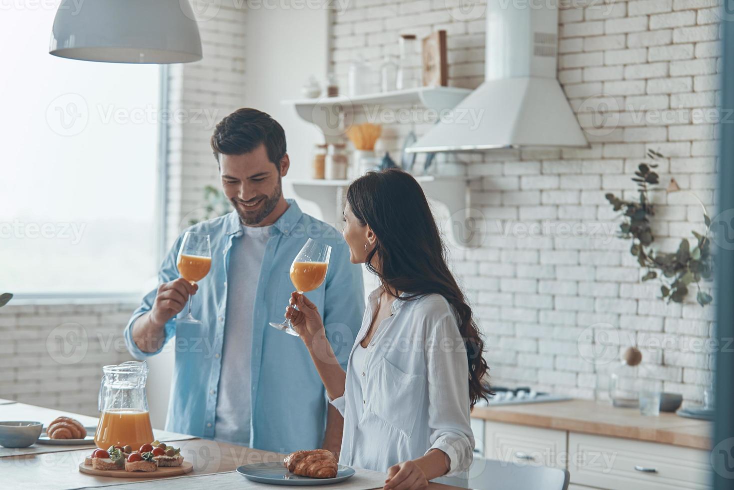 casal jovem feliz preparando o café da manhã juntos enquanto passa o tempo na cozinha doméstica foto