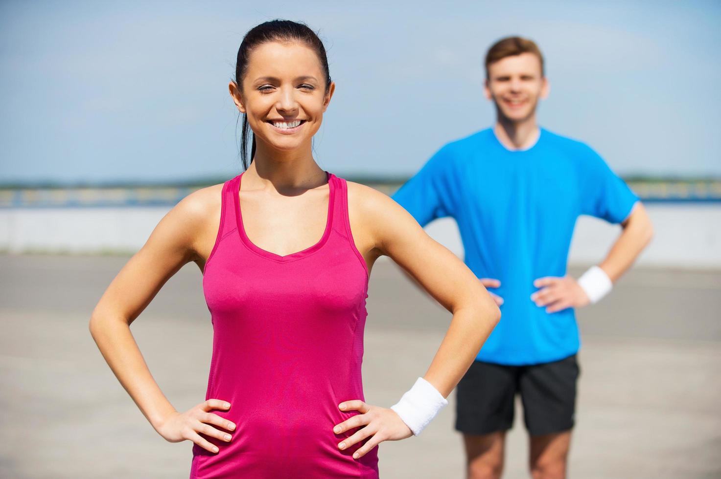 casal esportivo. jovem bonito em roupas esportivas, segurando as mãos no quadril em pé ao ar livre foto