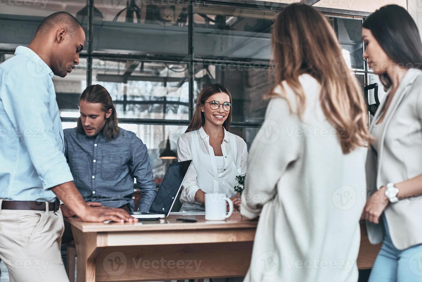 colaboração. grupo de jovens empresários se comunicando e sorrindo enquanto trabalhava no escritório foto