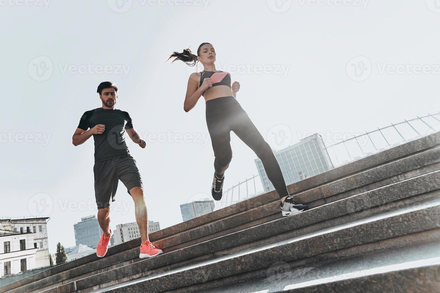 desafiando juntos. vista de ângulo baixo de comprimento total do jovem casal em roupas esportivas descendo as escadas juntos foto