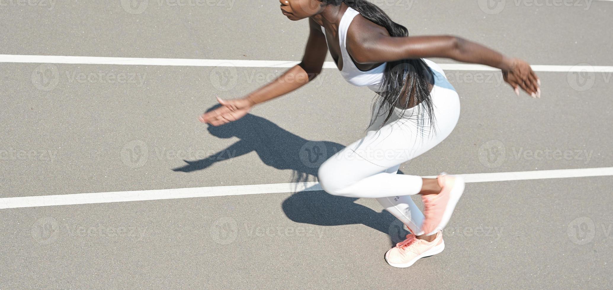 vista superior da bela jovem africana em roupas esportivas correndo na pista ao ar livre foto