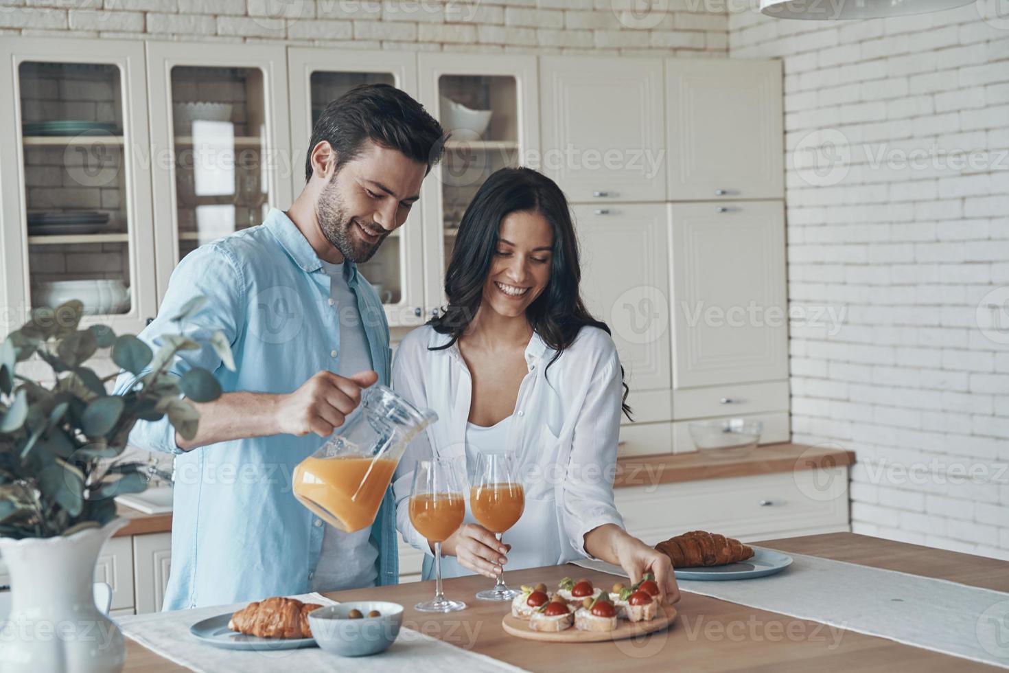 lindo casal jovem preparando o café da manhã juntos enquanto passa o tempo na cozinha doméstica foto