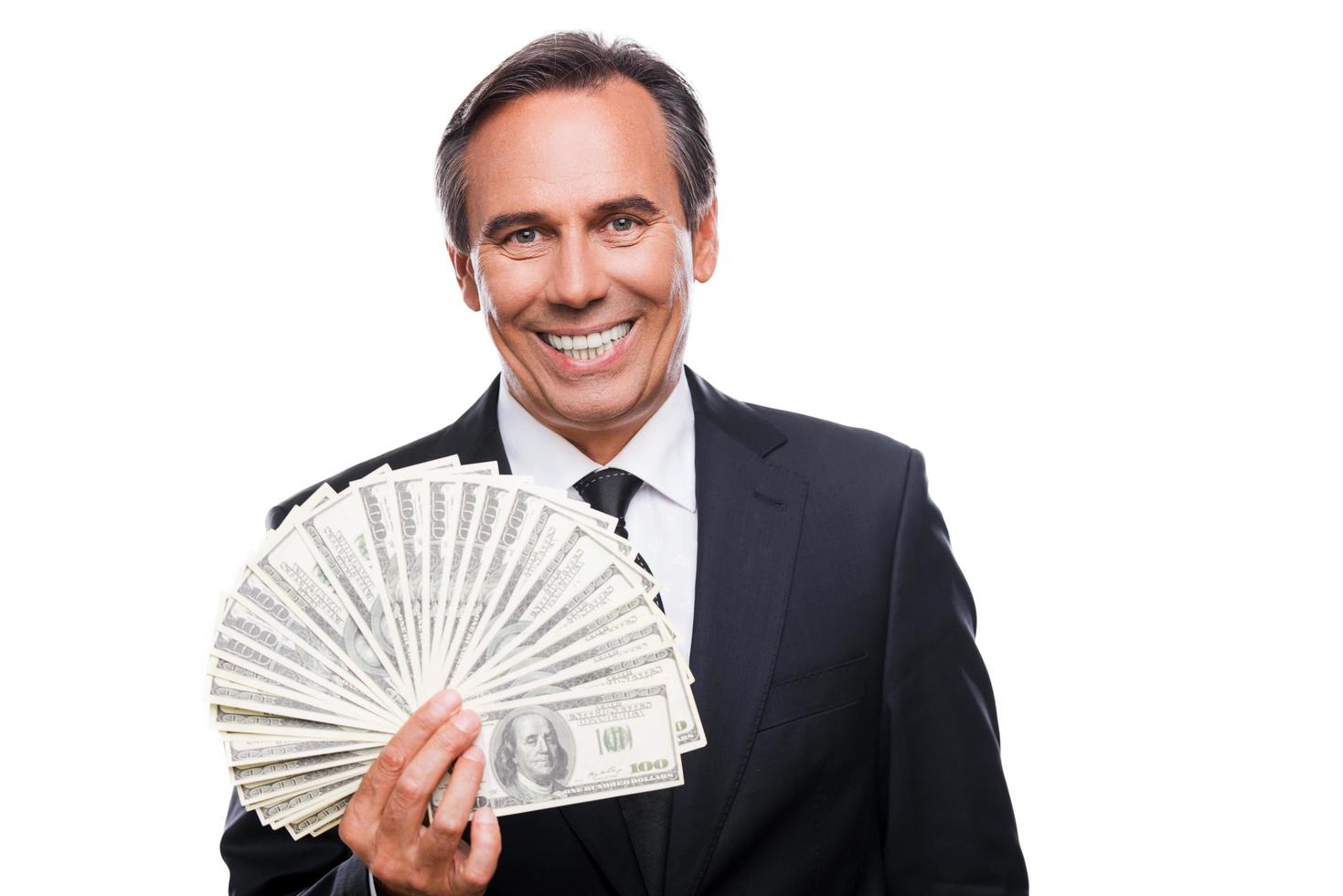 dinheiro é um poder. retrato de homem maduro confiante em trajes formais segurando dinheiro e sorrindo em pé contra um fundo branco foto
