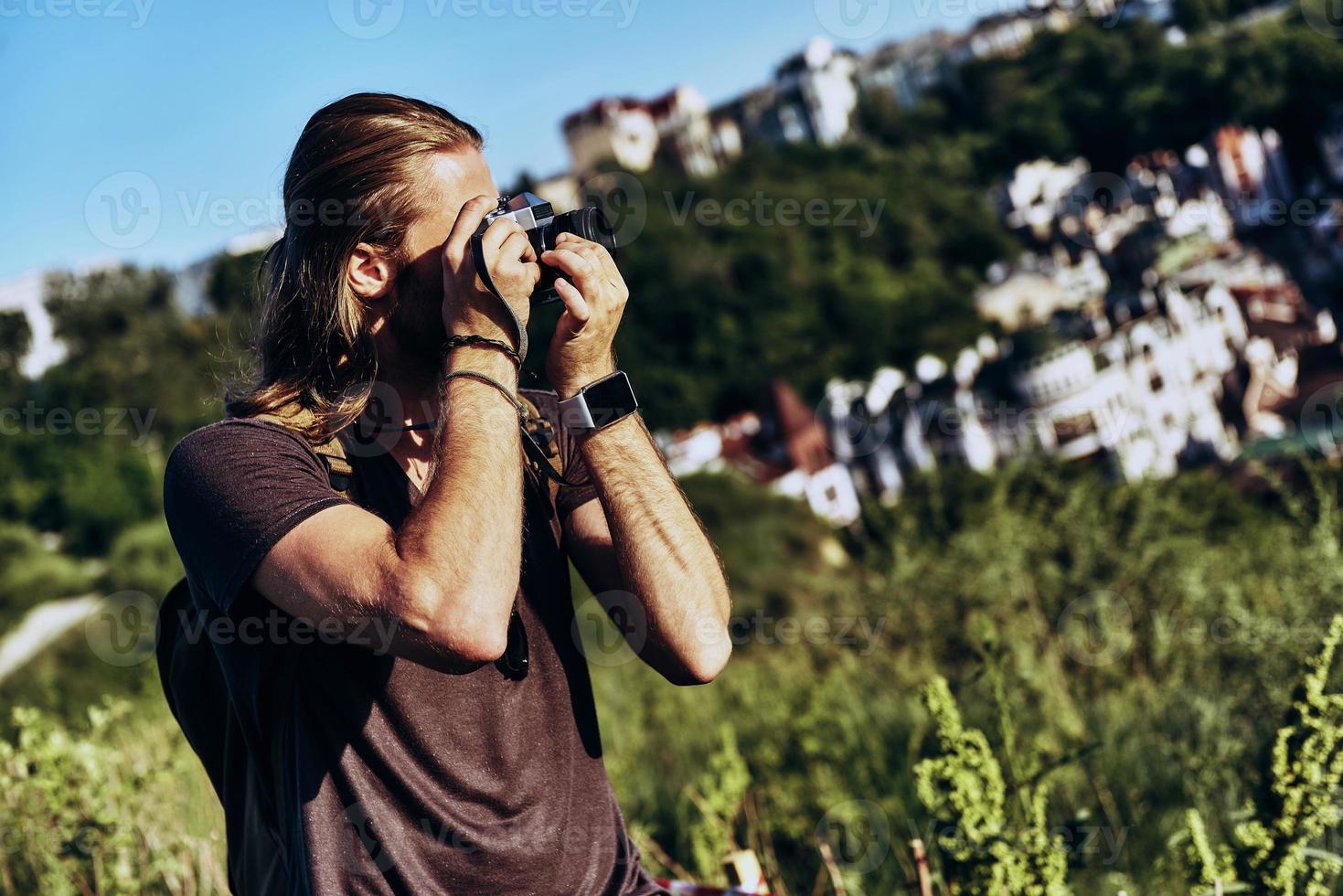 bom tiro. jovem em roupas casuais fotografando a vista em pé na colina ao ar livre foto