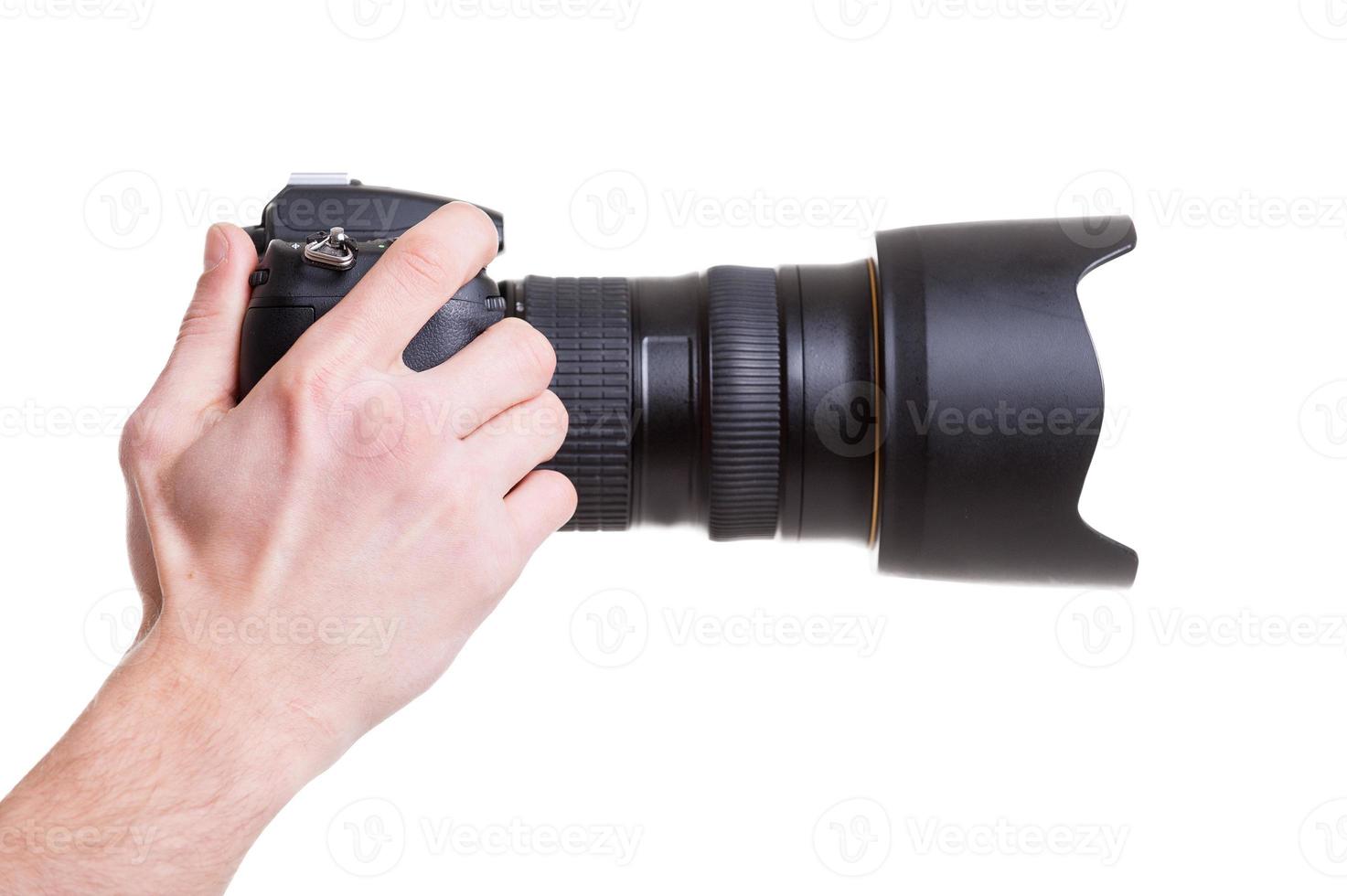câmera digital. vista lateral do homem segurando a câmera digital enquanto isolado no branco foto
