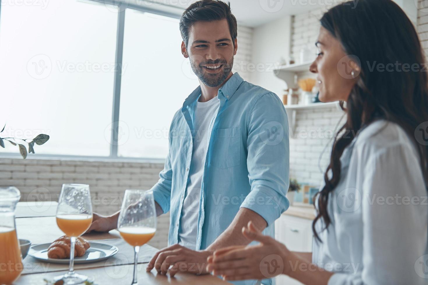 lindo casal jovem tomando café da manhã juntos enquanto passa o tempo na cozinha doméstica foto