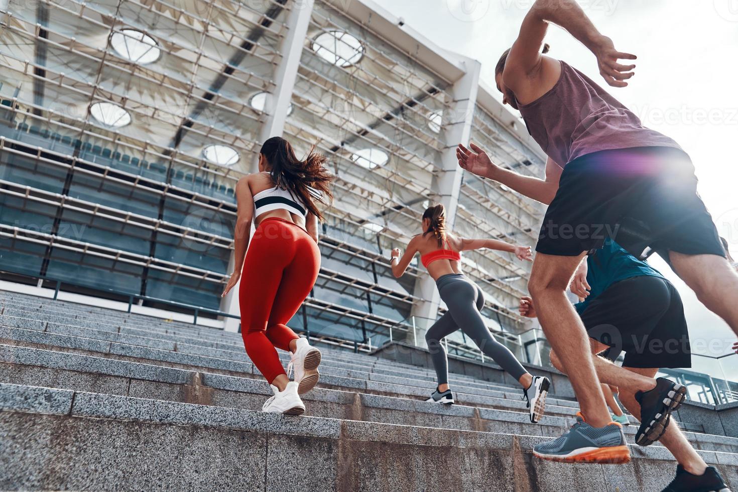 grupo de jovens em roupas esportivas correndo enquanto se exercita nas escadas ao ar livre foto