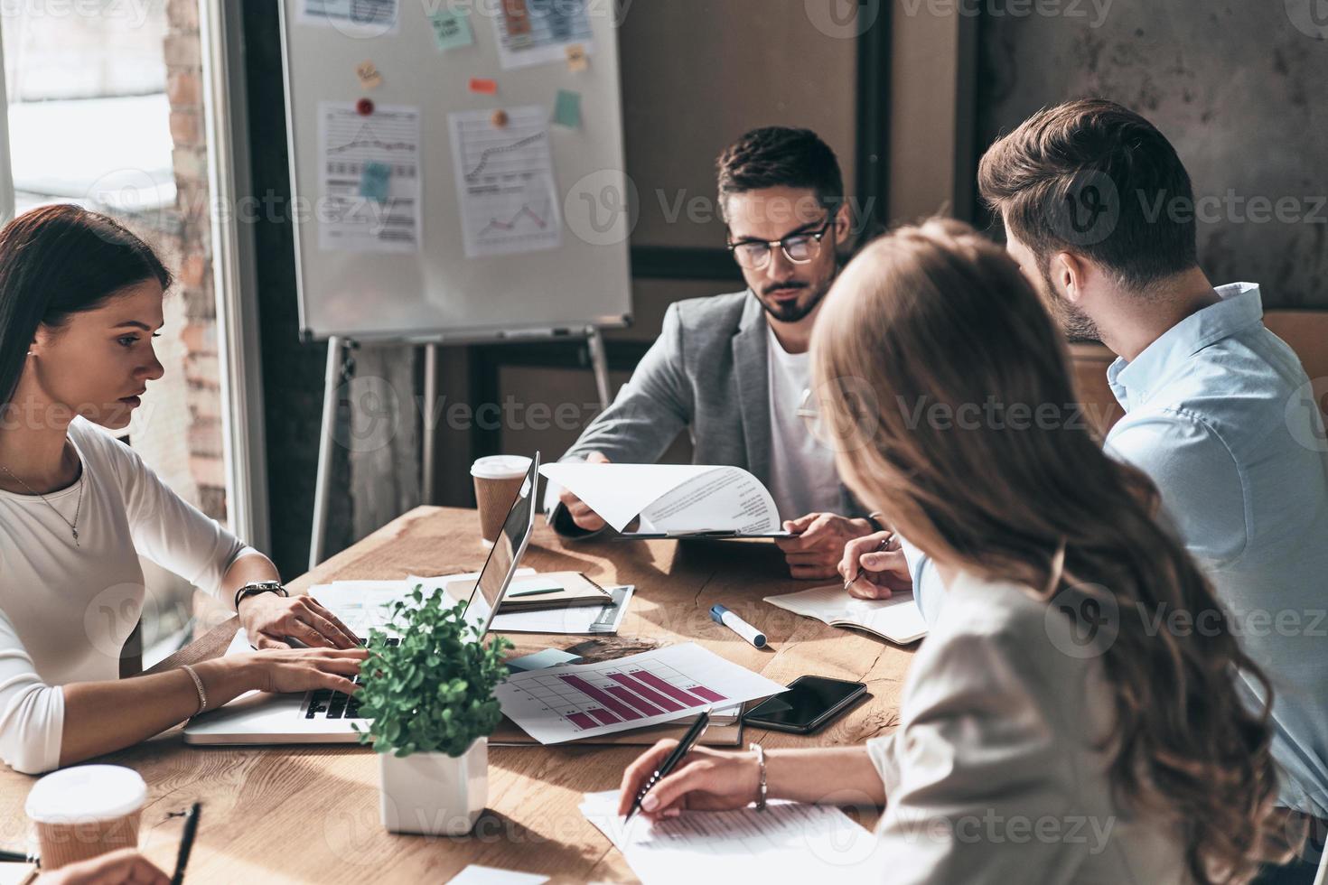 reunião importante. grupo de jovens modernos em roupas casuais inteligentes discutindo negócios enquanto está sentado no escritório criativo foto