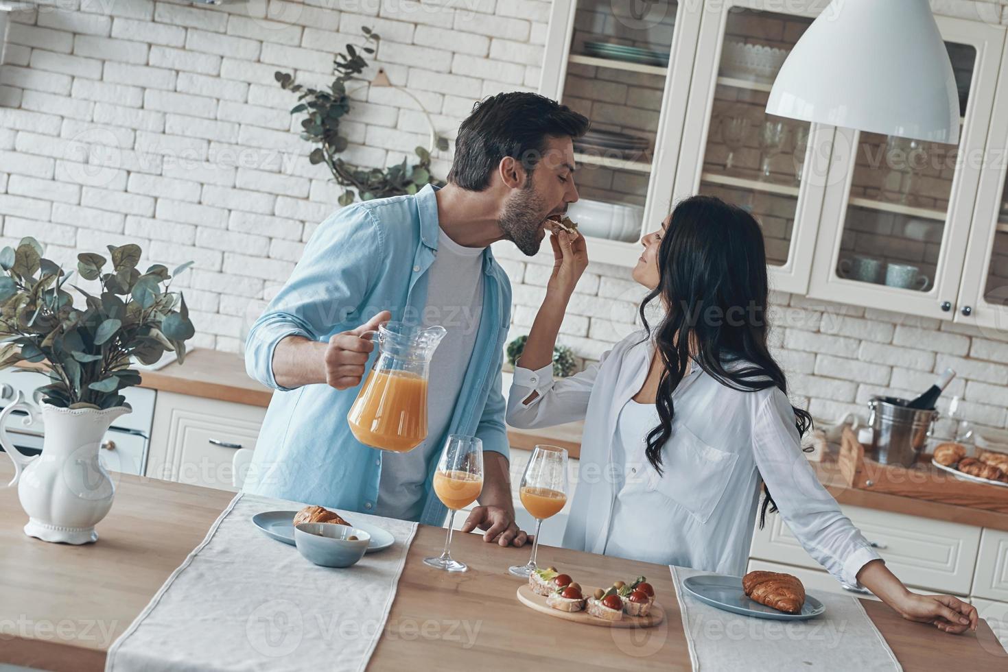 casal jovem feliz preparando o café da manhã juntos enquanto passa o tempo na cozinha doméstica foto