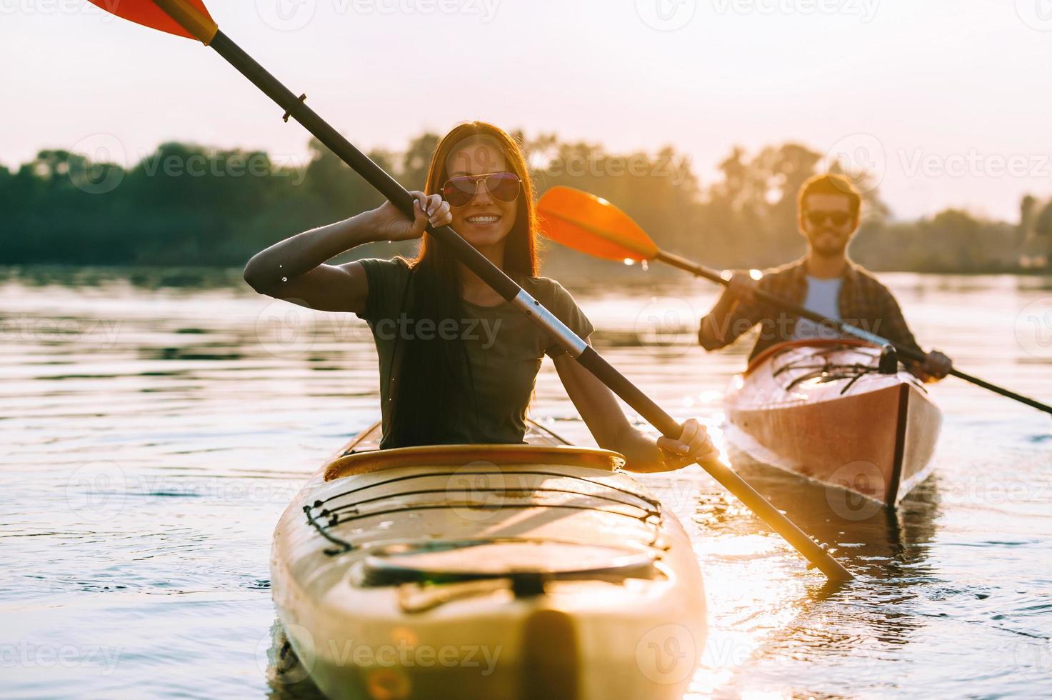 curtindo a aventura no rio. lindo casal jovem andando de caiaque no rio juntos e sorrindo foto