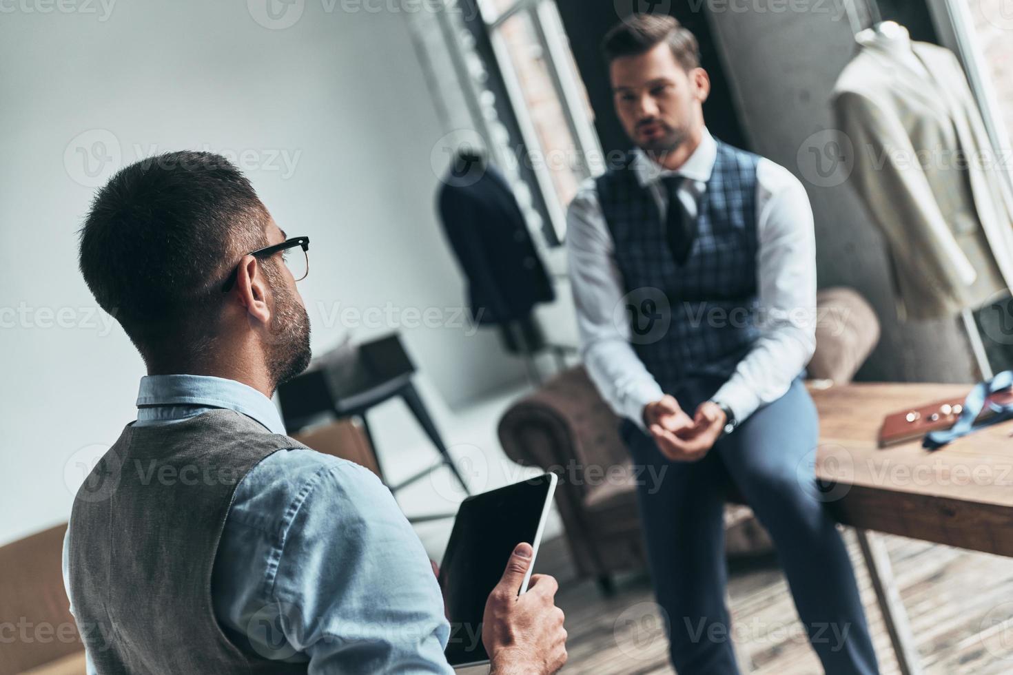 falando sobre moda. dois jovens elegantes discutindo enquanto passavam o tempo na oficina foto