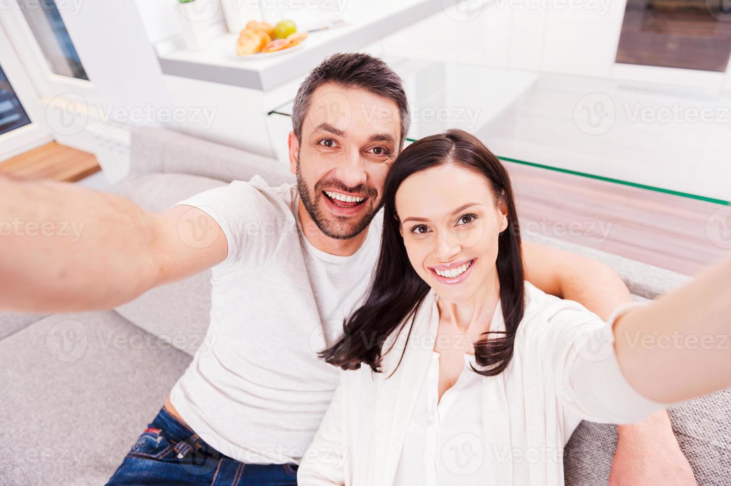 somos uma bela vista de cima de um casal amoroso feliz se unindo e fazendo selfie enquanto está sentado no sofá juntos foto