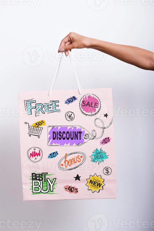 vantagens de compras. close-up da mão feminina segurando a sacola de compras com desenhos coloridos nele foto