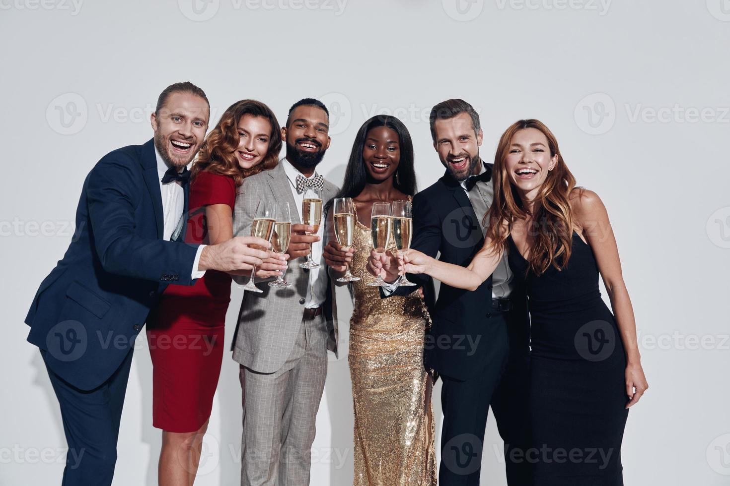 grupo de pessoas bonitas em trajes formais brindando com champanhe e sorrindo foto