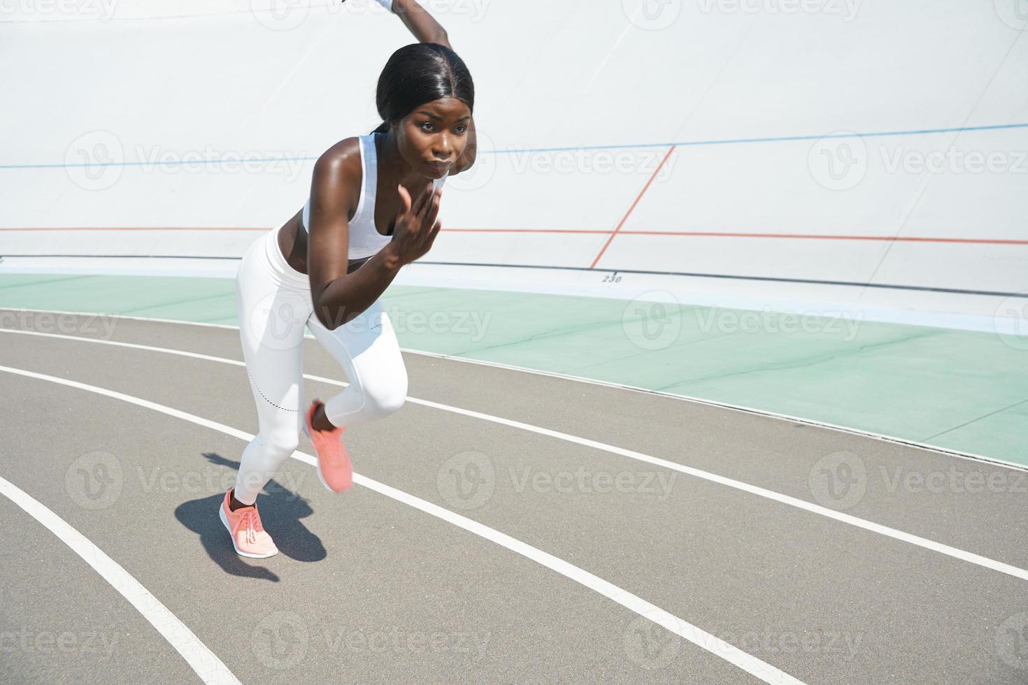 bela jovem africana em roupas esportivas correndo na pista ao ar livre foto