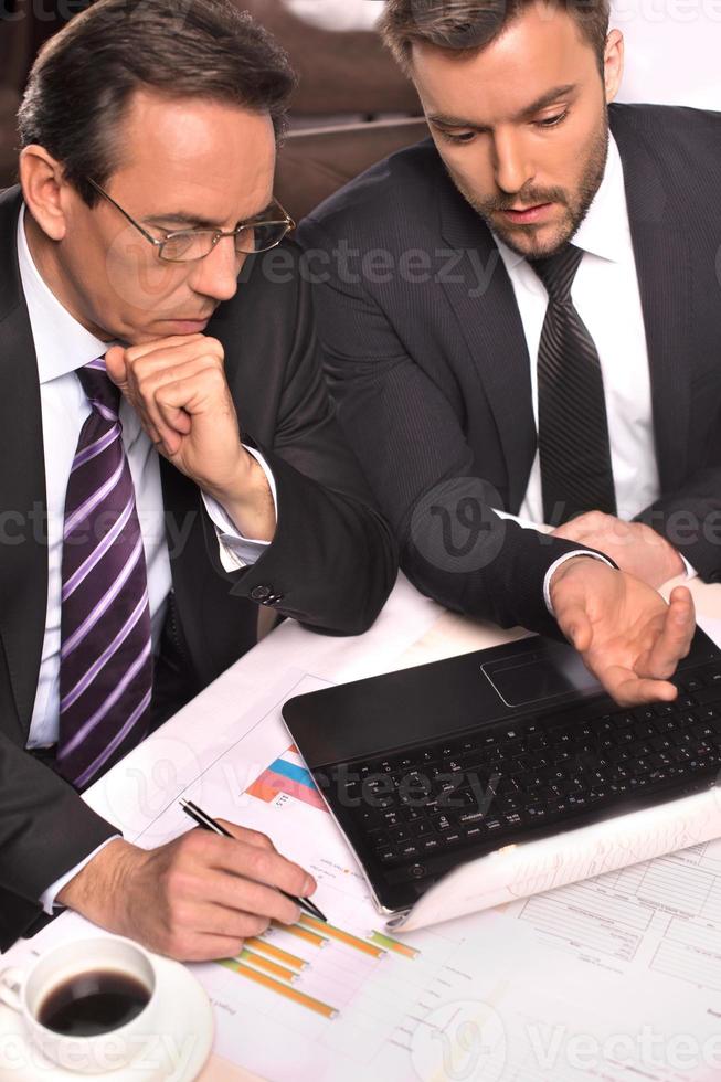 pessoas de negócios no trabalho. vista superior de dois empresários em trajes formais discutindo algo enquanto um deles aponta o monitor do computador foto