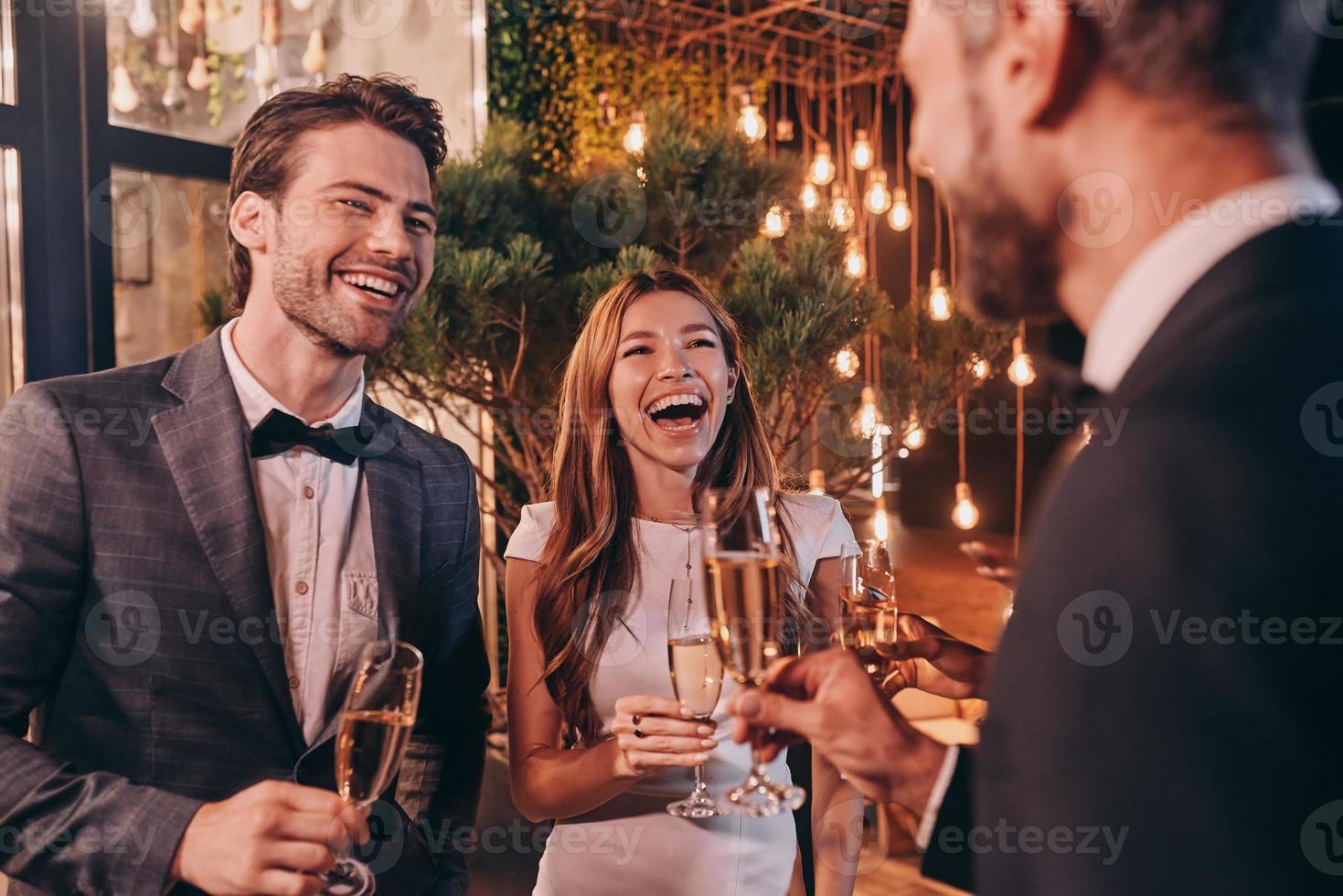 grupo de pessoas em trajes formais se comunicando e sorrindo enquanto passa o tempo na festa de luxo foto