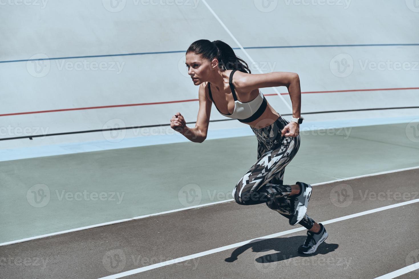 mulher jovem e bonita em roupas esportivas correndo enquanto se exercita ao ar livre foto