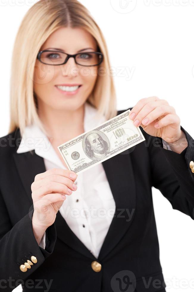 empresária madura confiante do dia de pagamento esticando as mãos com nota de cem dólares e sorrindo em pé isolado no branco foto