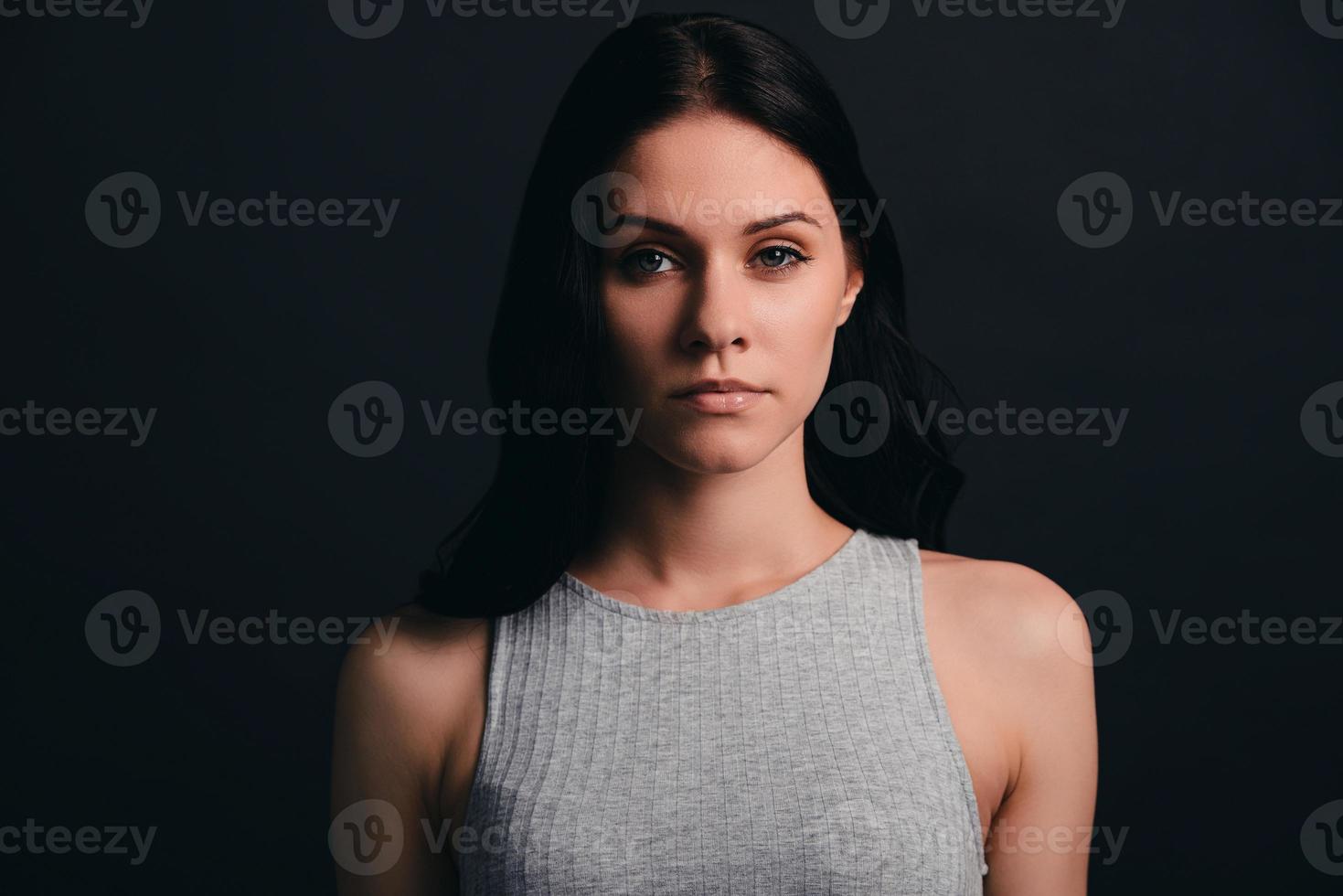 jovem e linda. retrato de mulher jovem e bonita olhando para a câmera em pé contra um fundo cinza foto