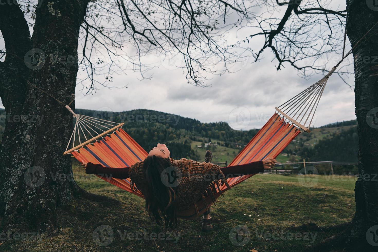 melhor lugar para descansar. bela jovem deitada na rede enquanto relaxa no vale debaixo da árvore foto