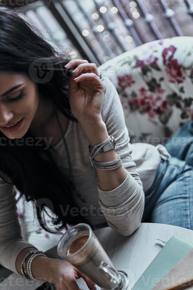 beleza Pura. atraente jovem sorridente tocando seu cabelo enquanto está sentado no restaurante foto