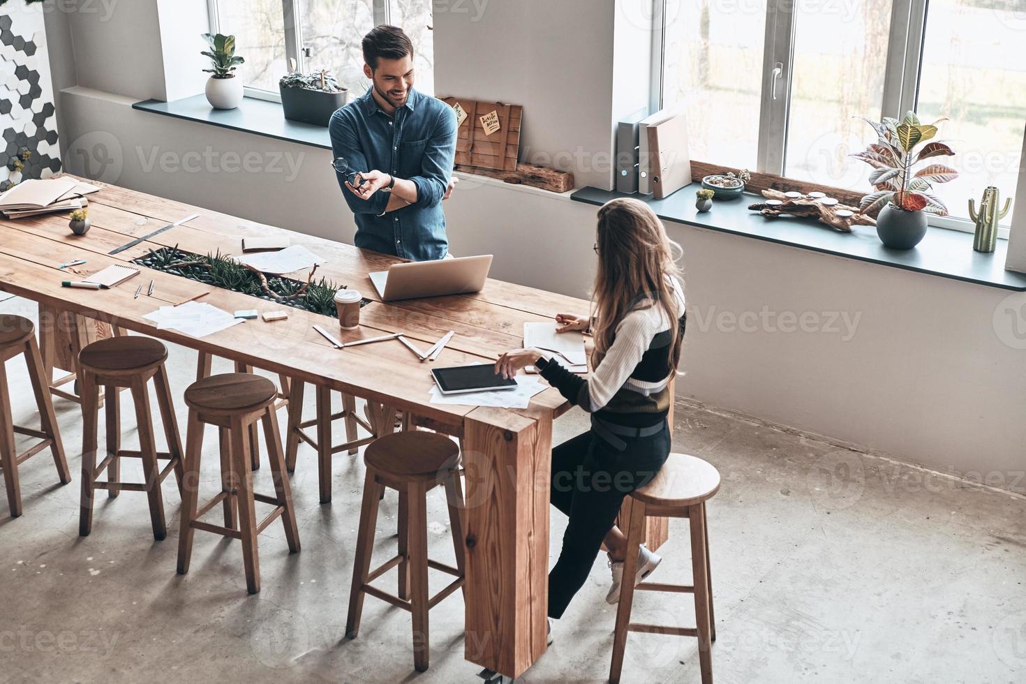 planejando outra etapa. vista superior de jovens colegas se comunicando e sorrindo enquanto passam o tempo no espaço de trabalho criativo foto