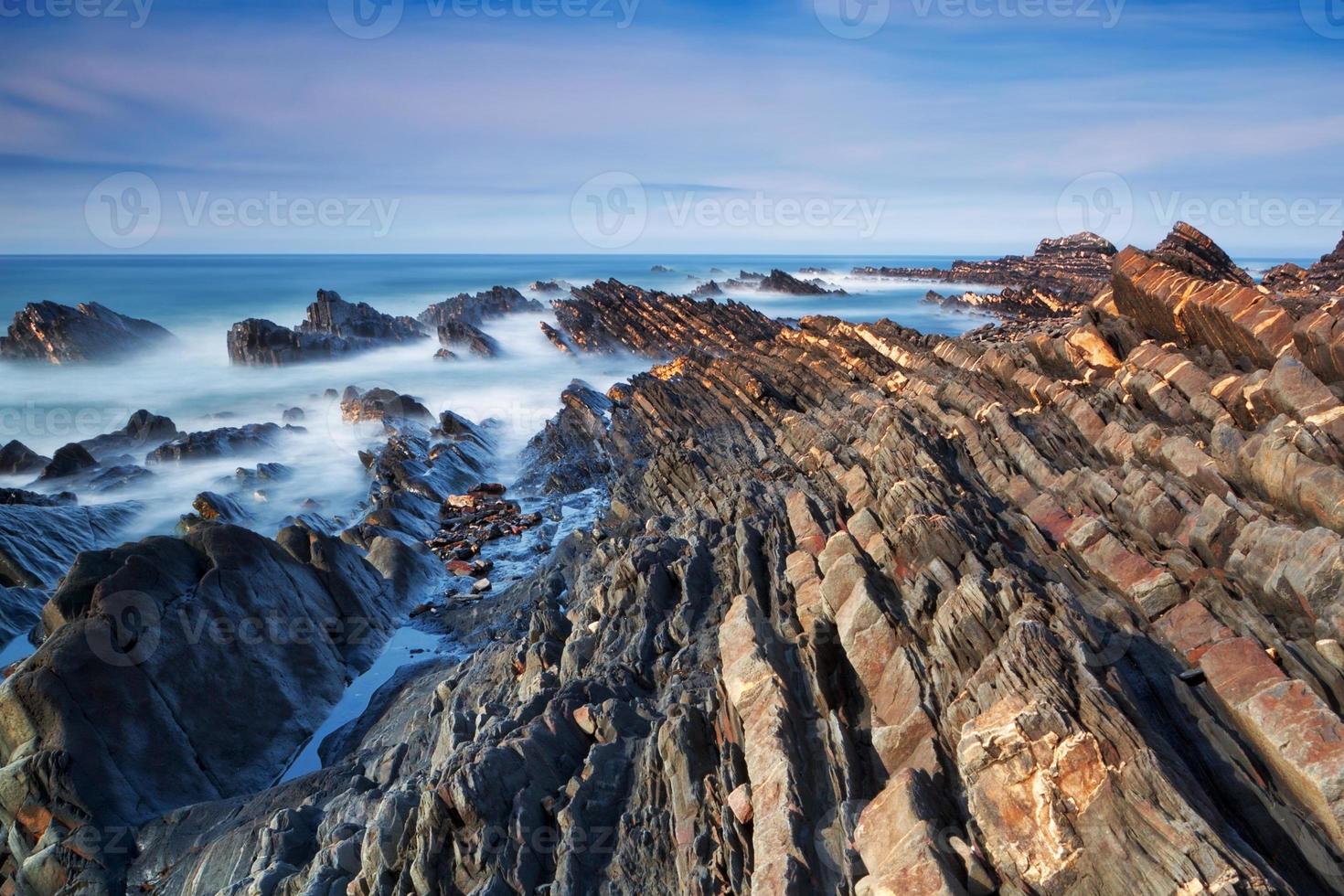 o oceano da costa rochosa marinha lava contra um céu azul dramático. foto