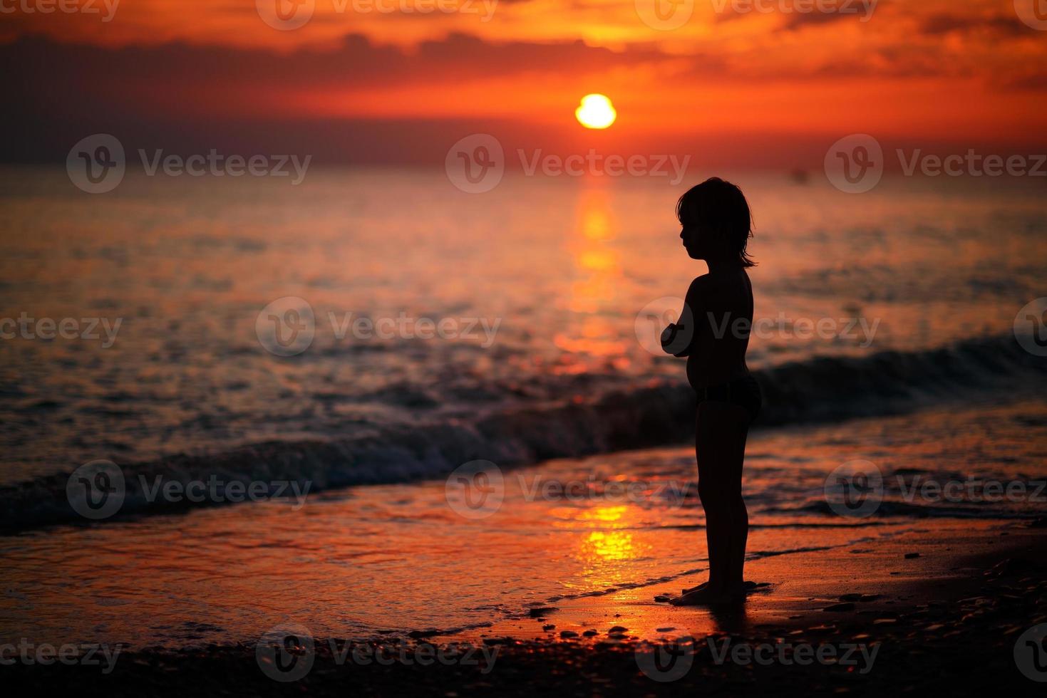 menino no mar ao pôr do sol foto