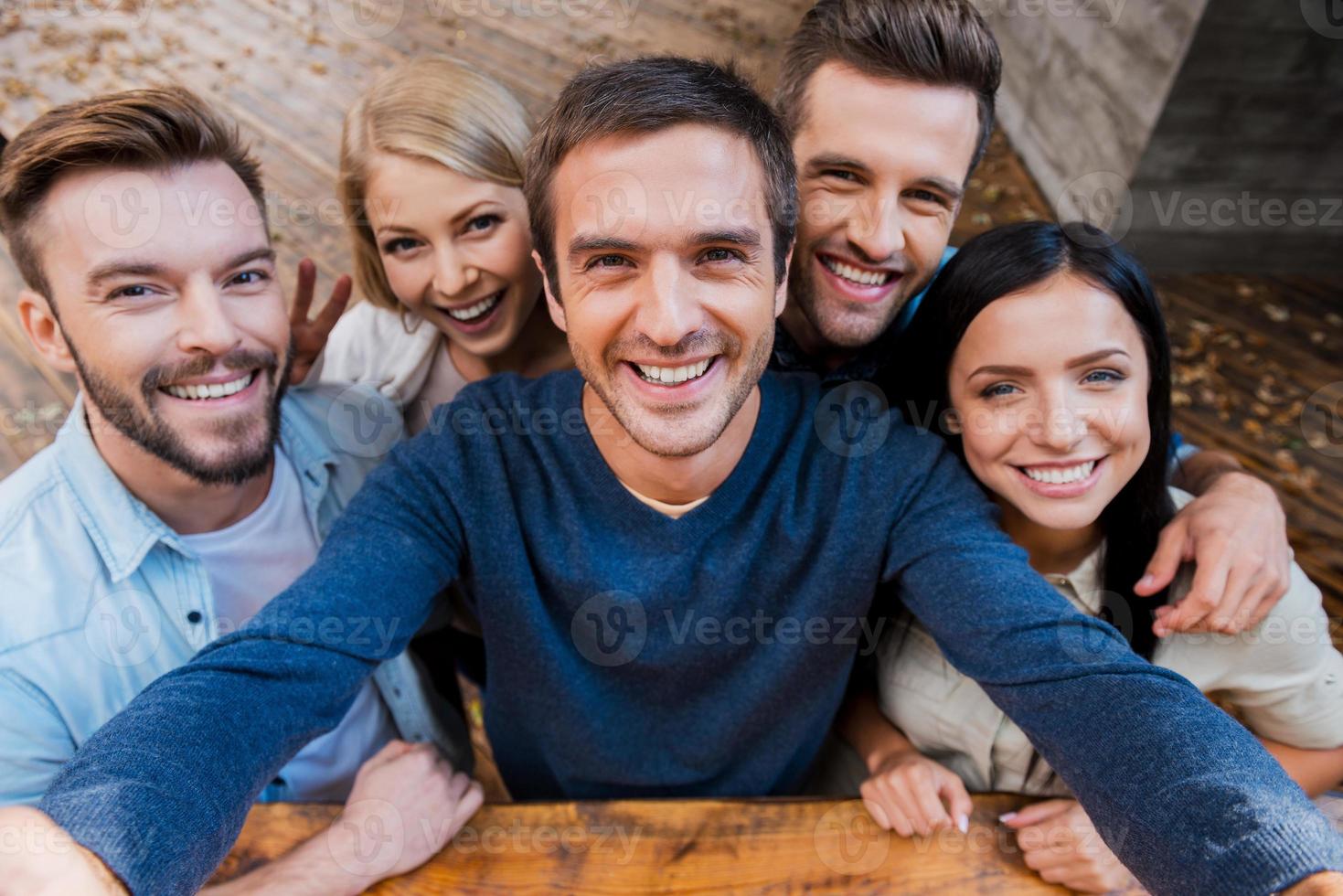 selfie engraçada com amigos. vista superior de cinco jovens alegres fazendo selfie e sorrindo em pé ao ar livre foto