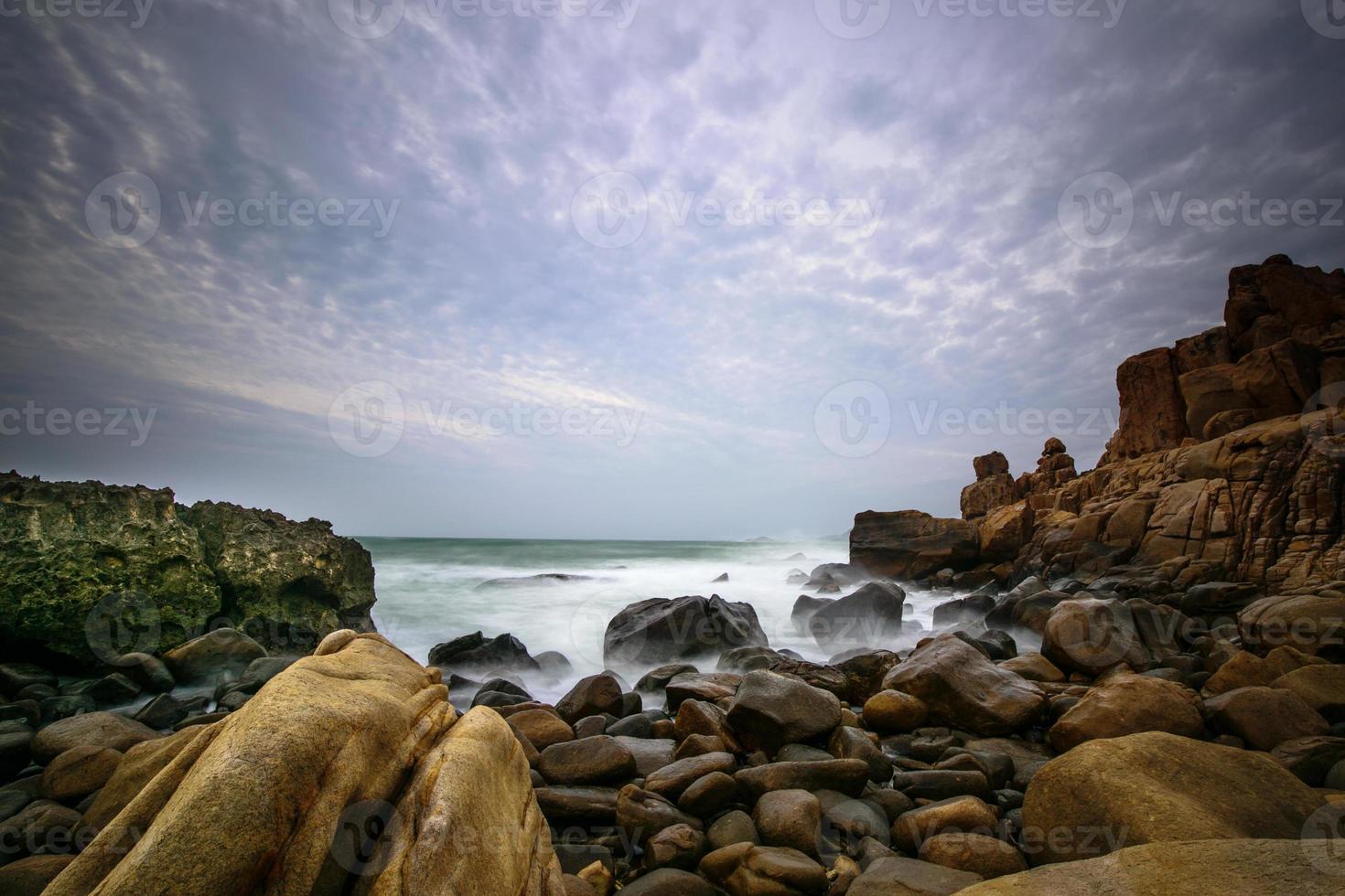 ondas quebrando na costa rochosa ao amanhecer foto