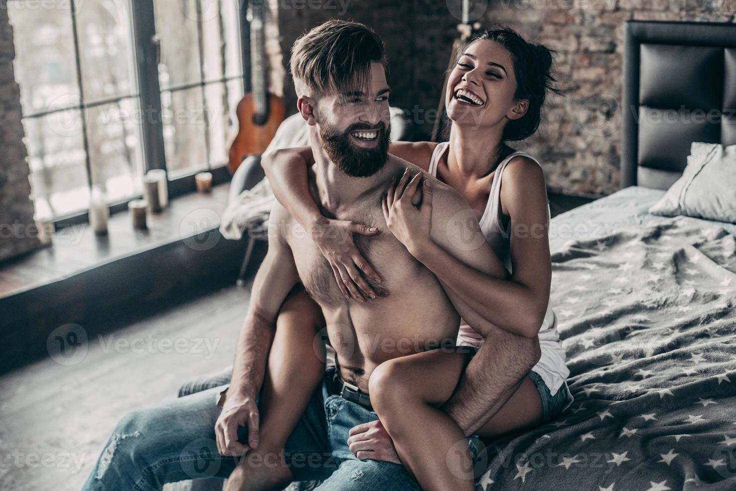 felizes juntos. atraente jovem casal sorrindo e se divertindo juntos enquanto linda garota mantendo os braços em volta do homem sem camisa foto