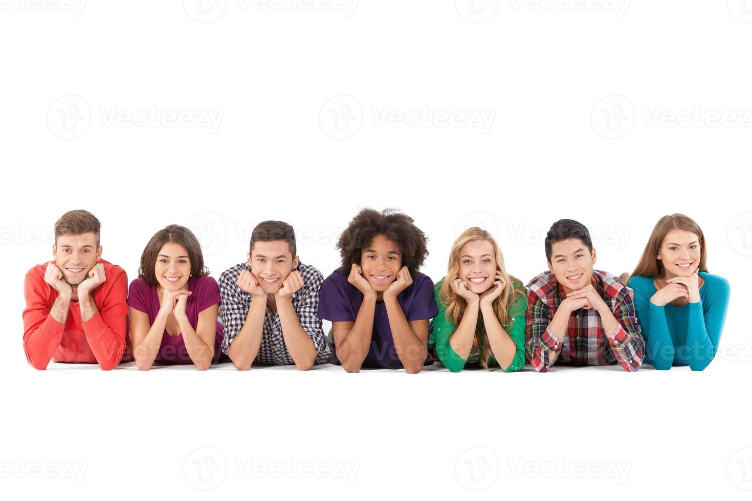 pessoas casuais. alegres jovens multiétnicas deitado na frente e sorrindo enquanto isolados no branco foto
