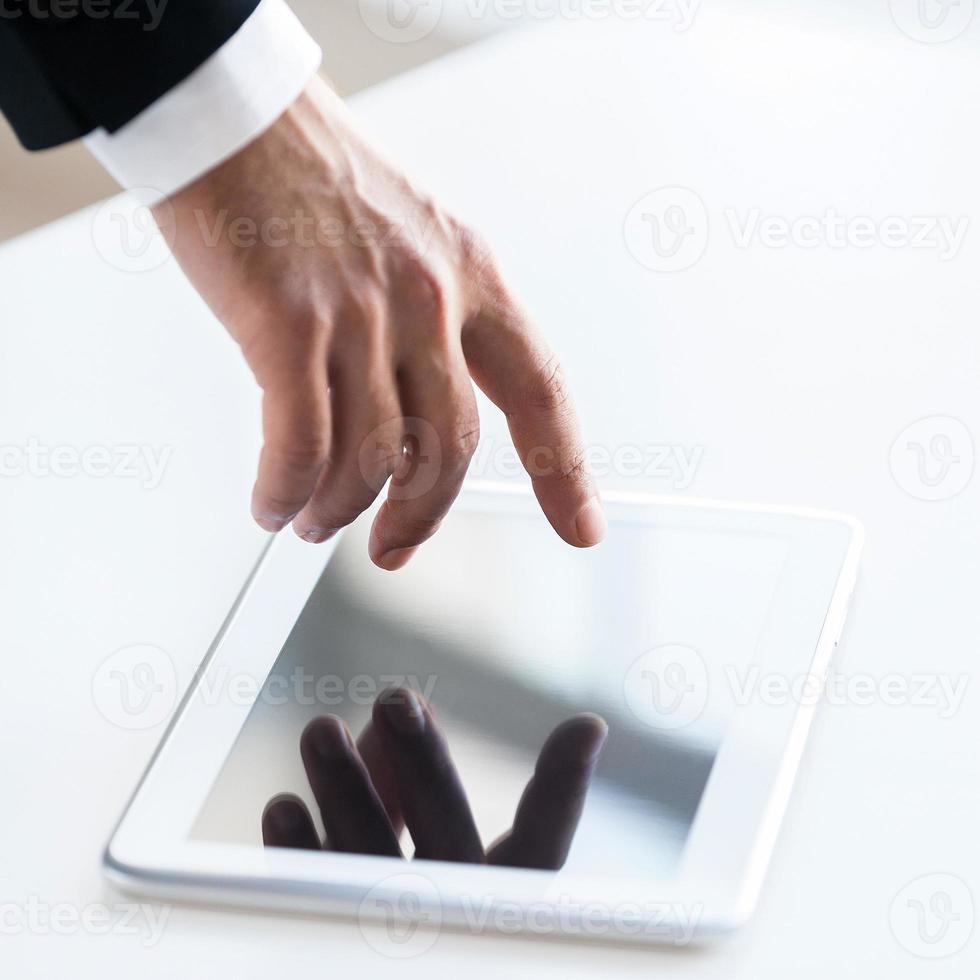 junte-se a uma visão superior da era digital da mão humana tocando uma tela de tablet digital sobre a mesa foto