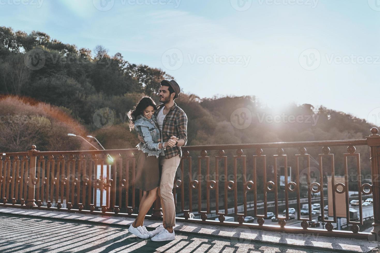 simplesmente apaixonado. comprimento total de lindo casal jovem dançando em pé na ponte ao ar livre foto