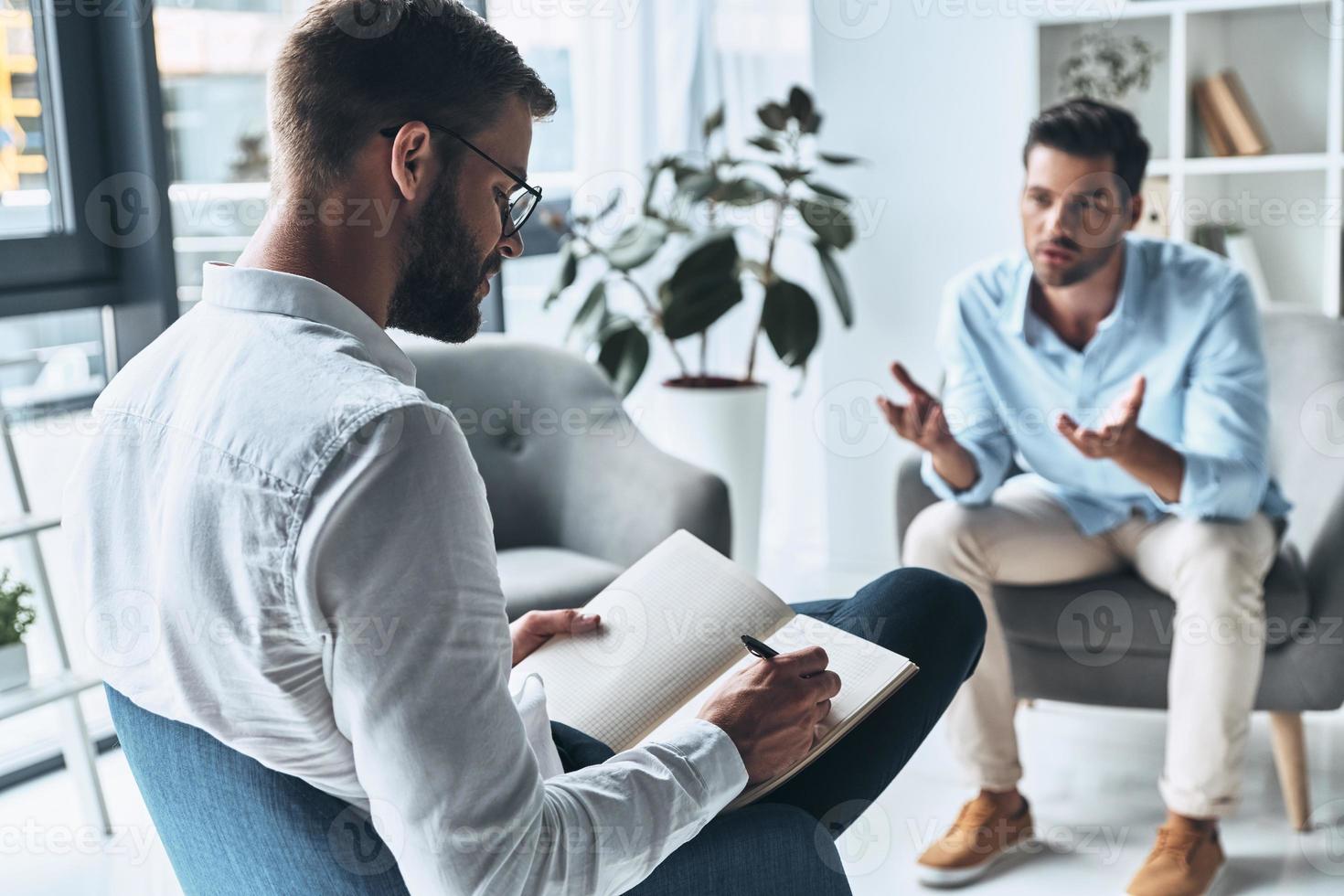 todos precisam de apoio. jovem frustrado falando e gesticulando enquanto está sentado na sessão de terapia com psicólogo foto