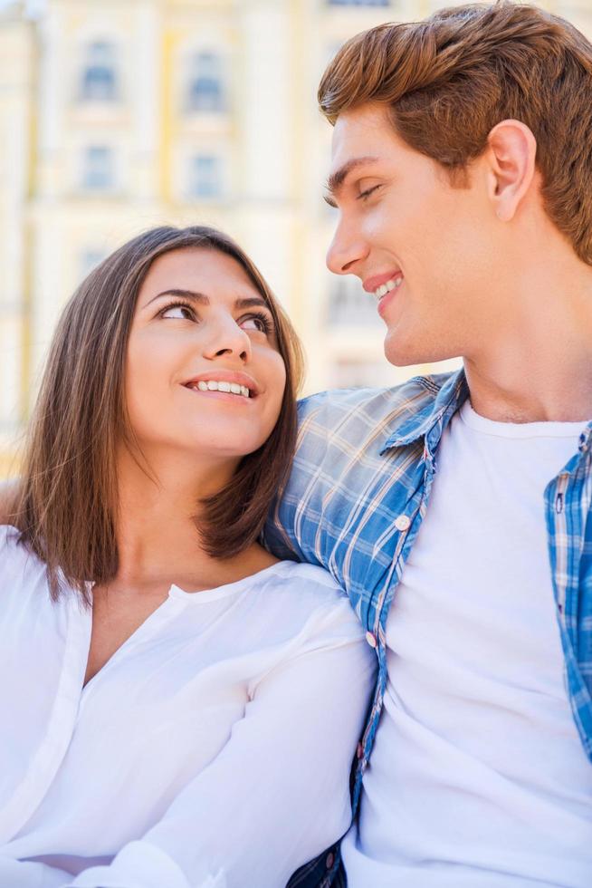 feliz casal apaixonado. lindo jovem casal apaixonado sentado no banco juntos e olhando para cada um foto