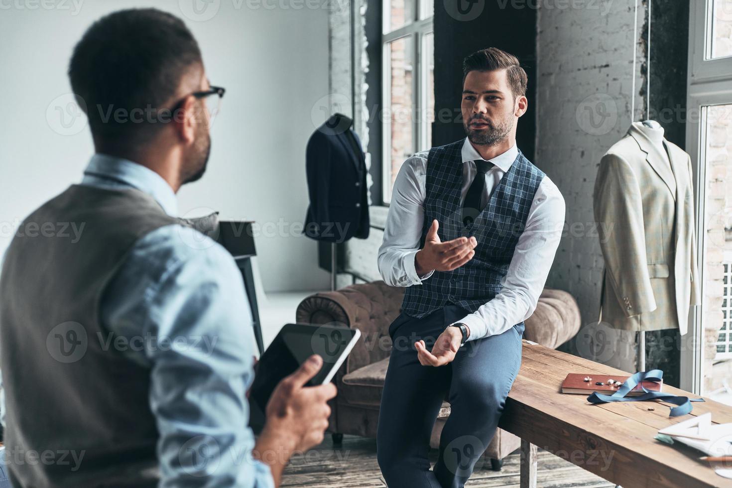 trabalhando alguns conceitos. dois jovens elegantes discutindo enquanto passavam o tempo na oficina foto