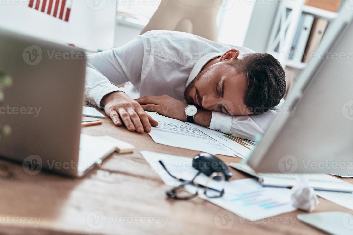 trabalhando até tarde. jovem cansado em trajes formais dormindo na mesa enquanto trabalhava até tarde foto