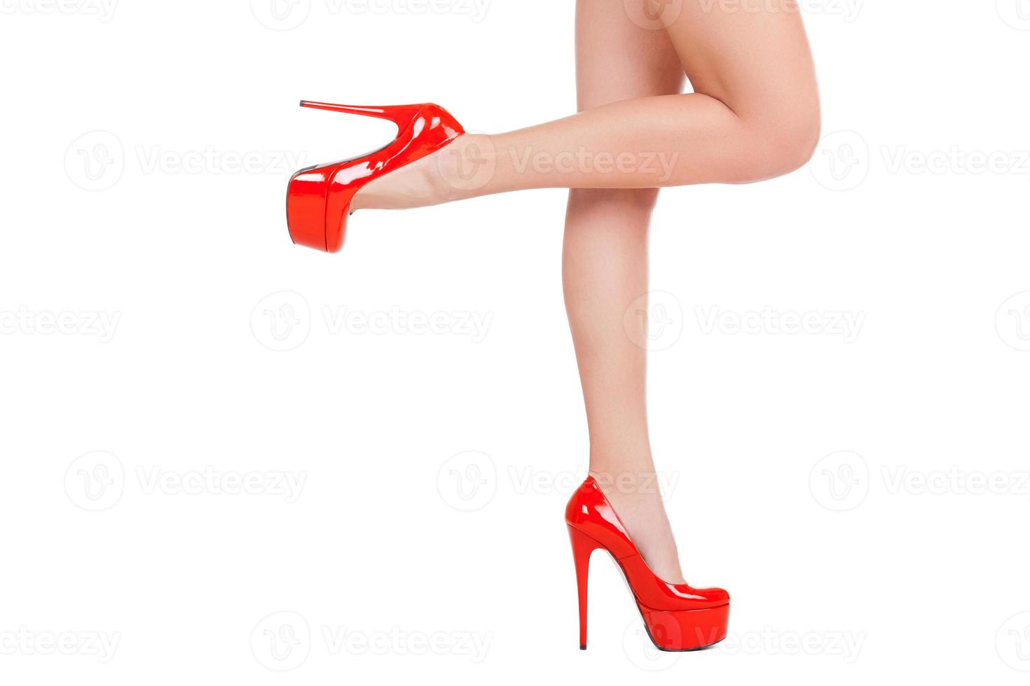 graça e elegância. Vista lateral de close-up de mulher bonita em sapatos vermelhos de salto alto posando em pé isolado no branco foto