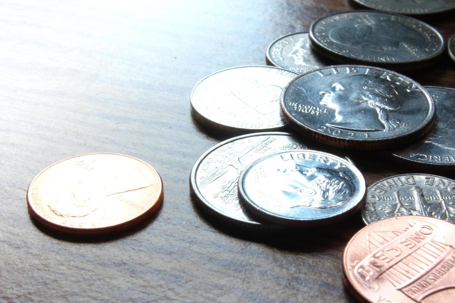 moedas de dólar espalhadas em uma mesa de madeira, foto