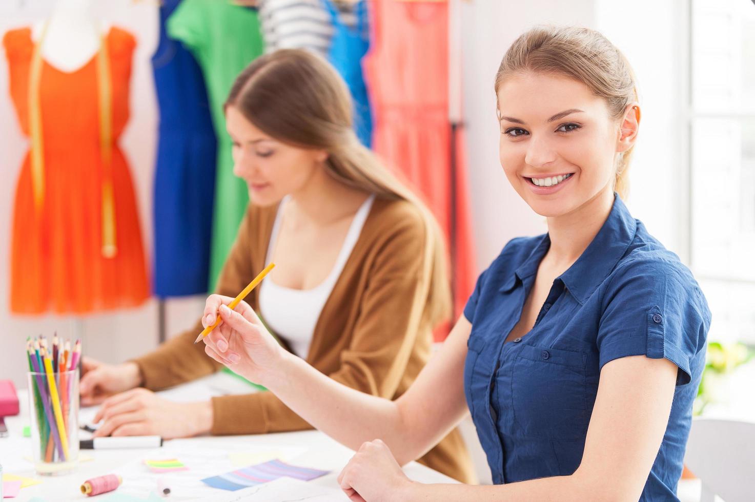 designers de moda confiantes. bela designer de moda feminina olhando para a câmera e sorrindo enquanto está sentado junto com seu colega foto