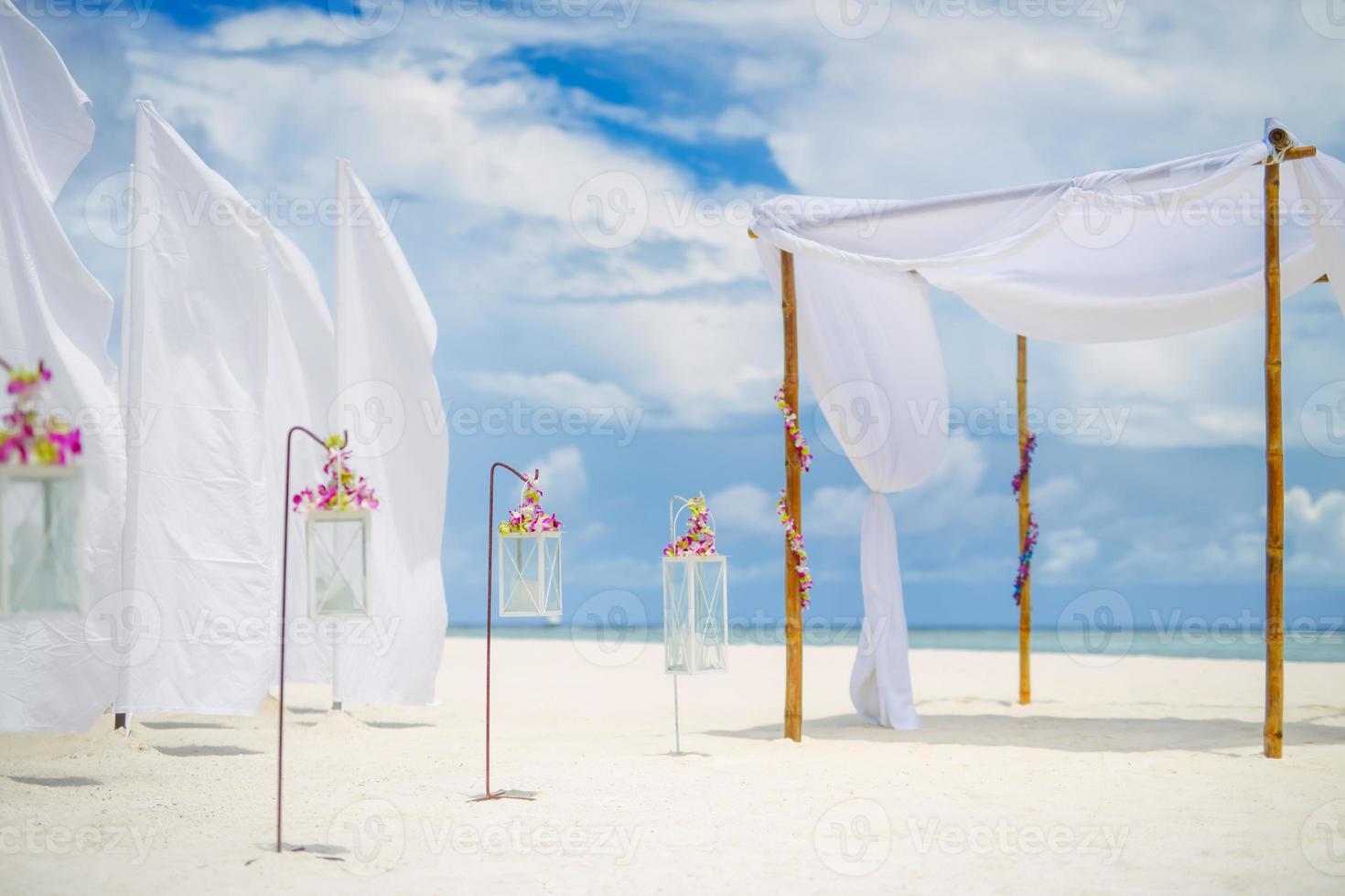 lindo casamento na praia. decoração branca com flores de orquídeas e velas sobre areia branca. casamento de destino romântico idílico ou lua de mel, celebração ao ar livre. conceito de casamento na praia foto