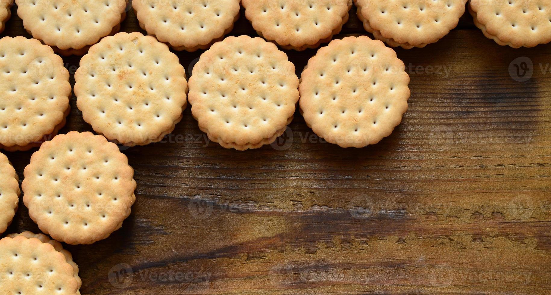 um biscoito redondo com recheio de coco está em grandes quantidades em uma superfície de madeira marrom. foto de guloseimas comestíveis em um fundo de madeira com espaço de cópia