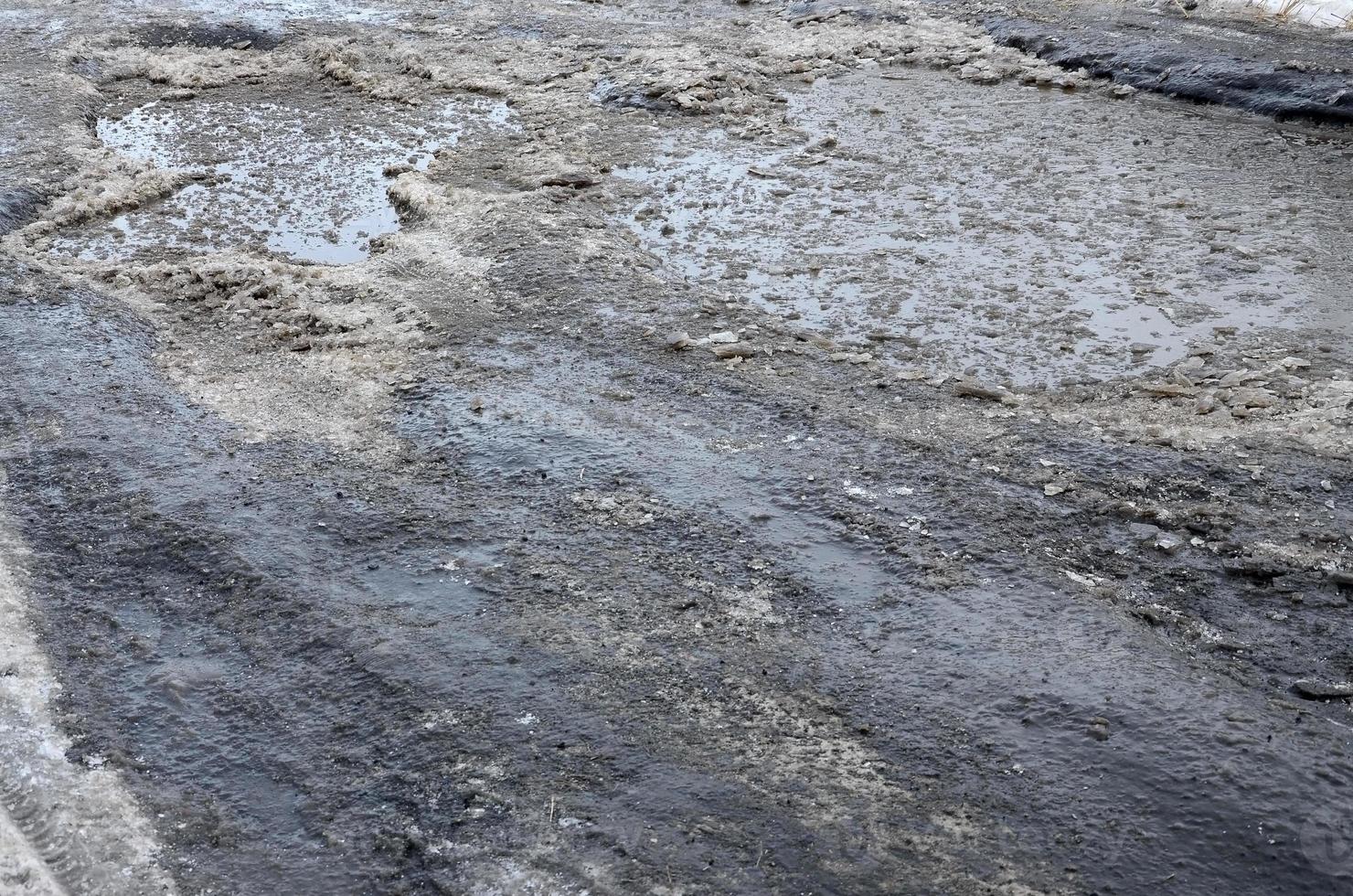 estrada de asfalto danificada com buracos causados por ciclos de congelamento e degelo durante o inverno. estrada pobre foto