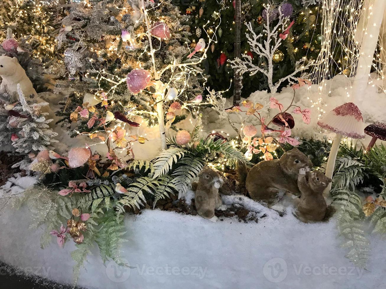 decorações de ano novo para o centro comercial. árvores de natal artificiais com iluminação. em um monte de neve ursos, esquilos e furões. animais artificiais comemoram o ano novo foto