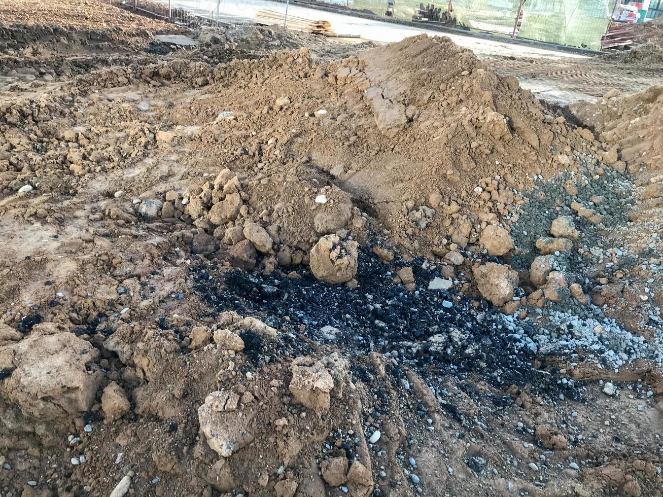 um monte de areia empilhado em um canteiro de obras. óleo combustível preto e viscoso é derramado no chão. materiais de construção para a construção de novas casas. pedras e detritos na areia foto