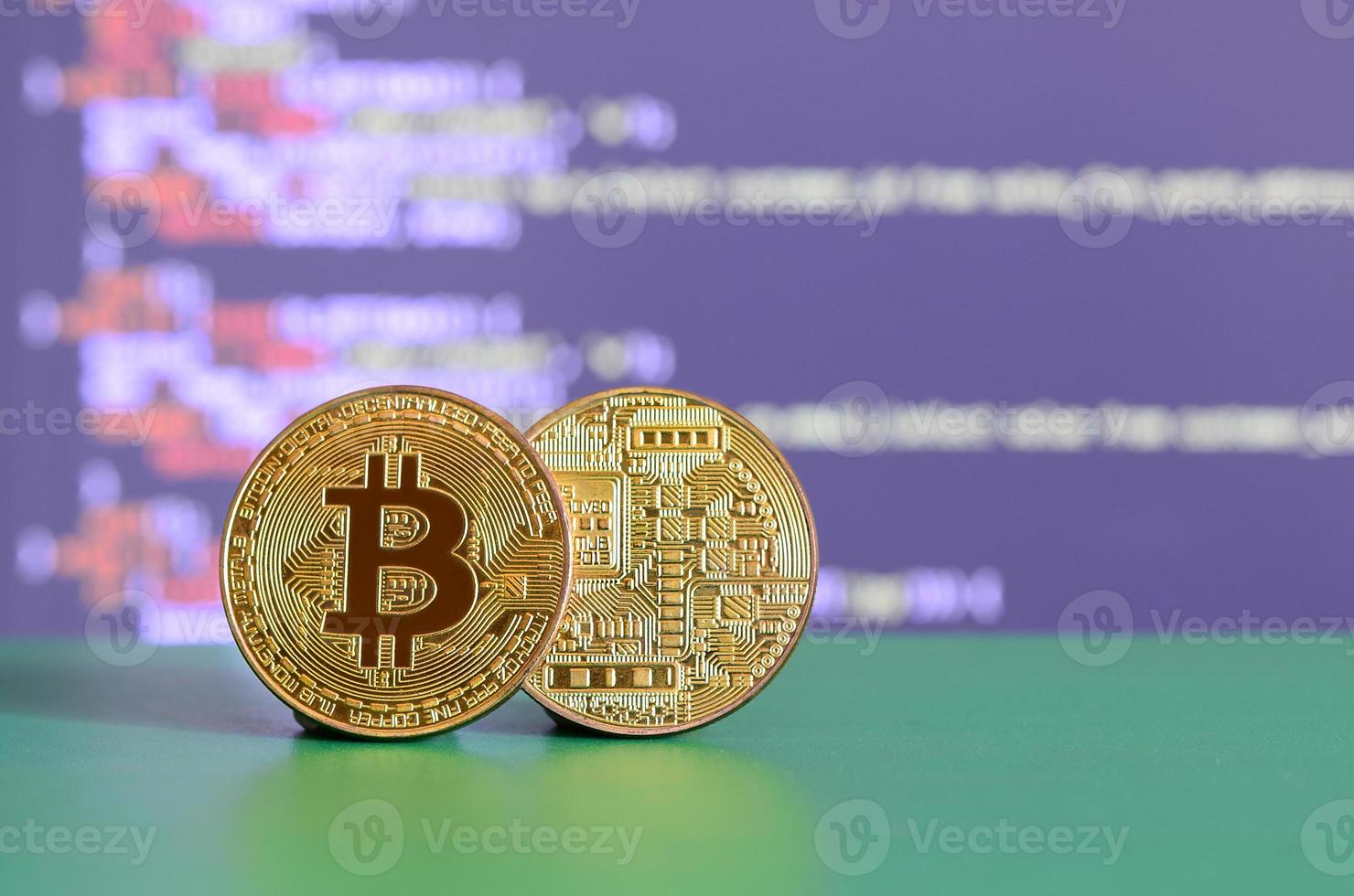 dois bitcoins de ouro estão na superfície verde no fundo da tela, que mostra o processo de mineração da moeda criptográfica foto