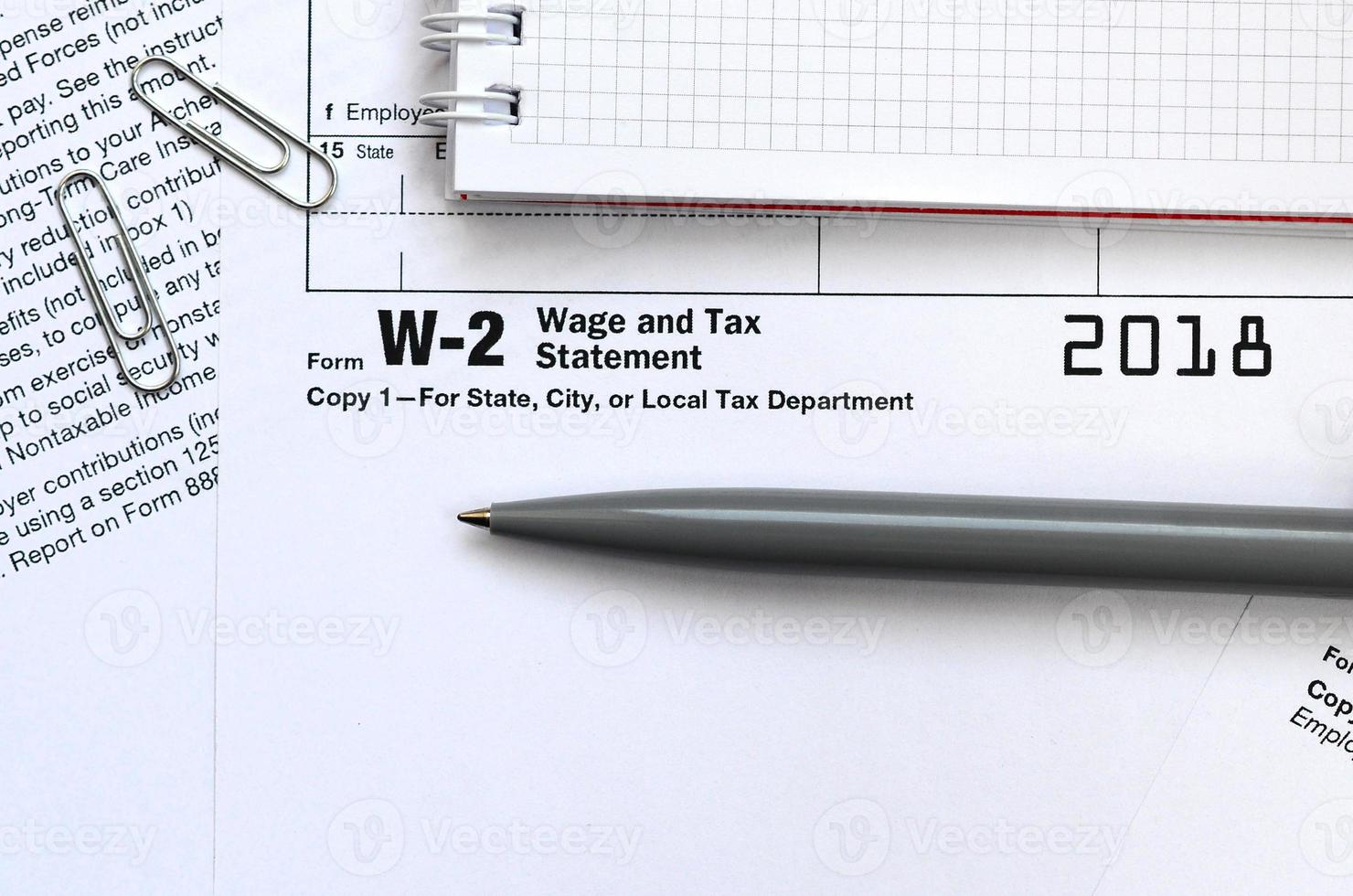a caneta e o caderno no formulário de imposto w-2 declaração de salário e imposto. hora de pagar impostos foto